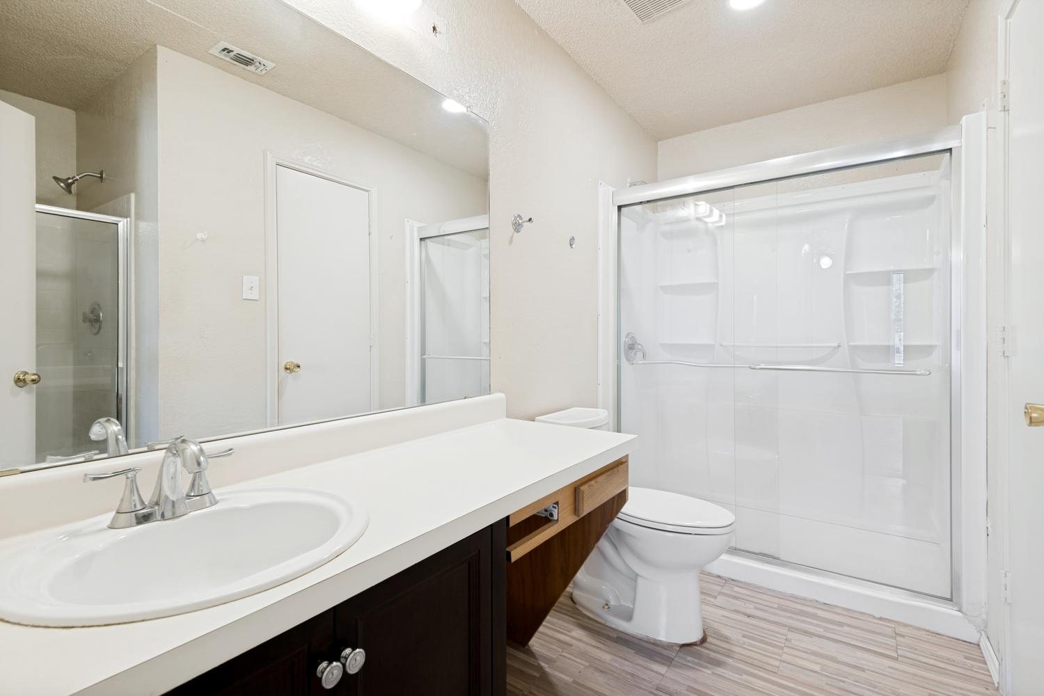 Bathroom with a sink, wall-to-wall mirror and a glass-door shower