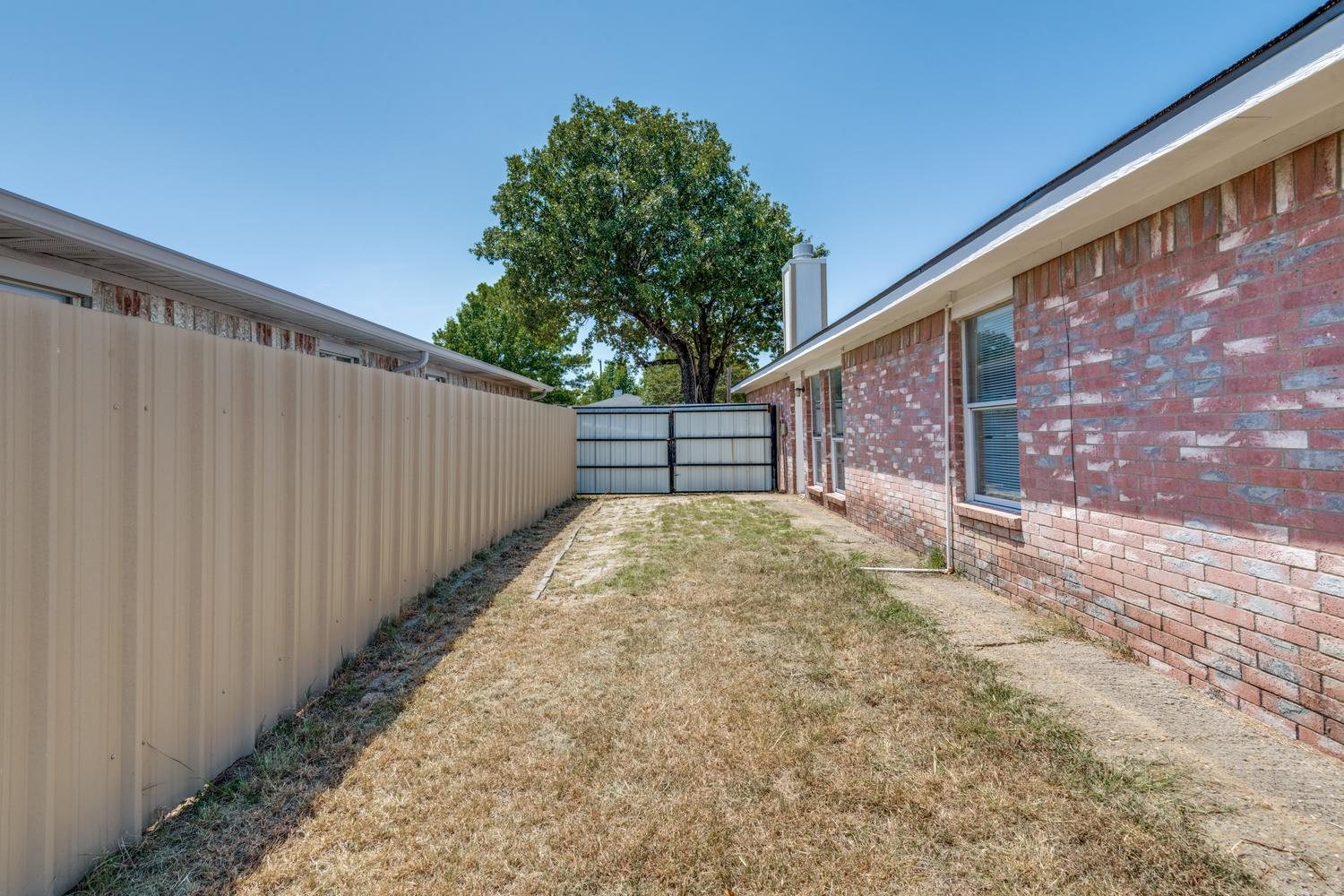Fenced side yard, with a large tree in the back