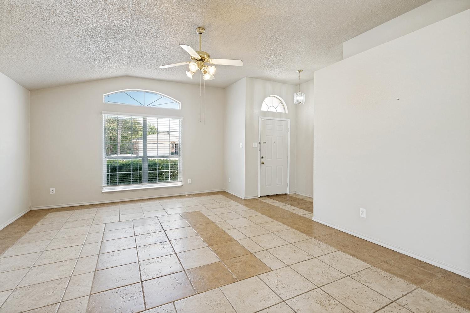 Living room with a high ceiling, arched window and tile floor