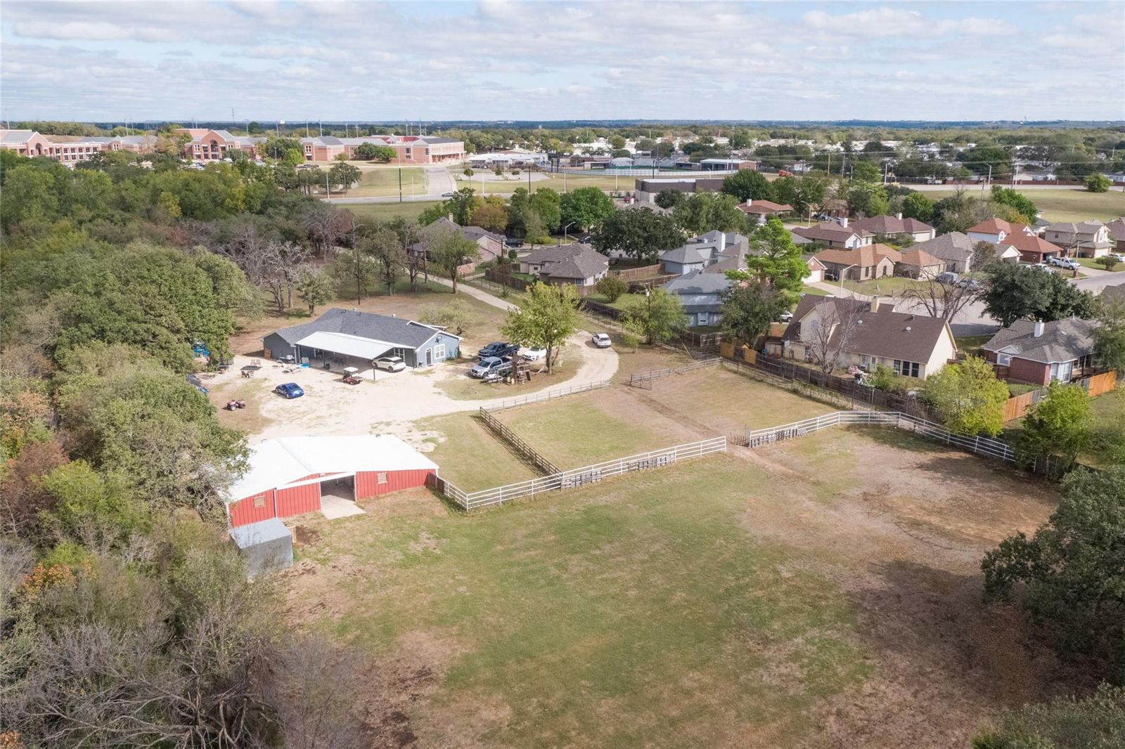 Aerial view of the property with the home, the red barn and open land
