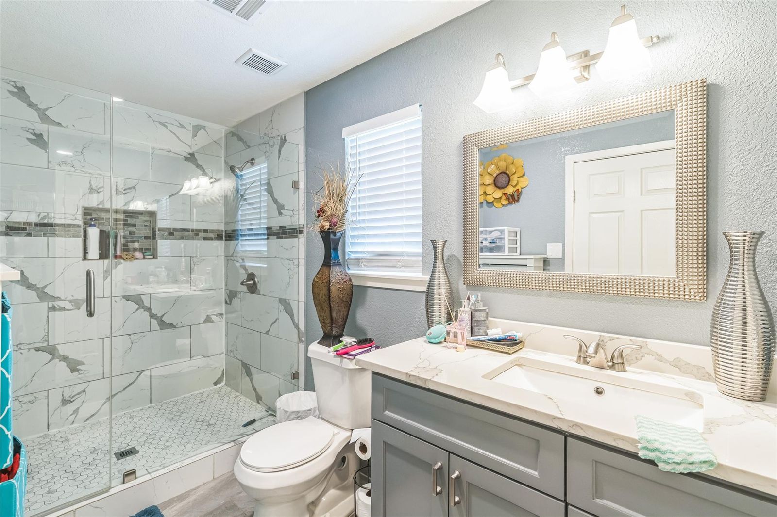 Remodeled bathroom with a glass shower and gray vanity